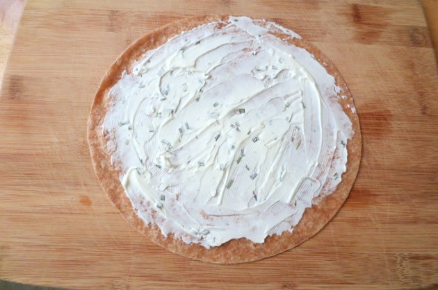 Spread a thin, even layer of the cream cheese on the tortilla